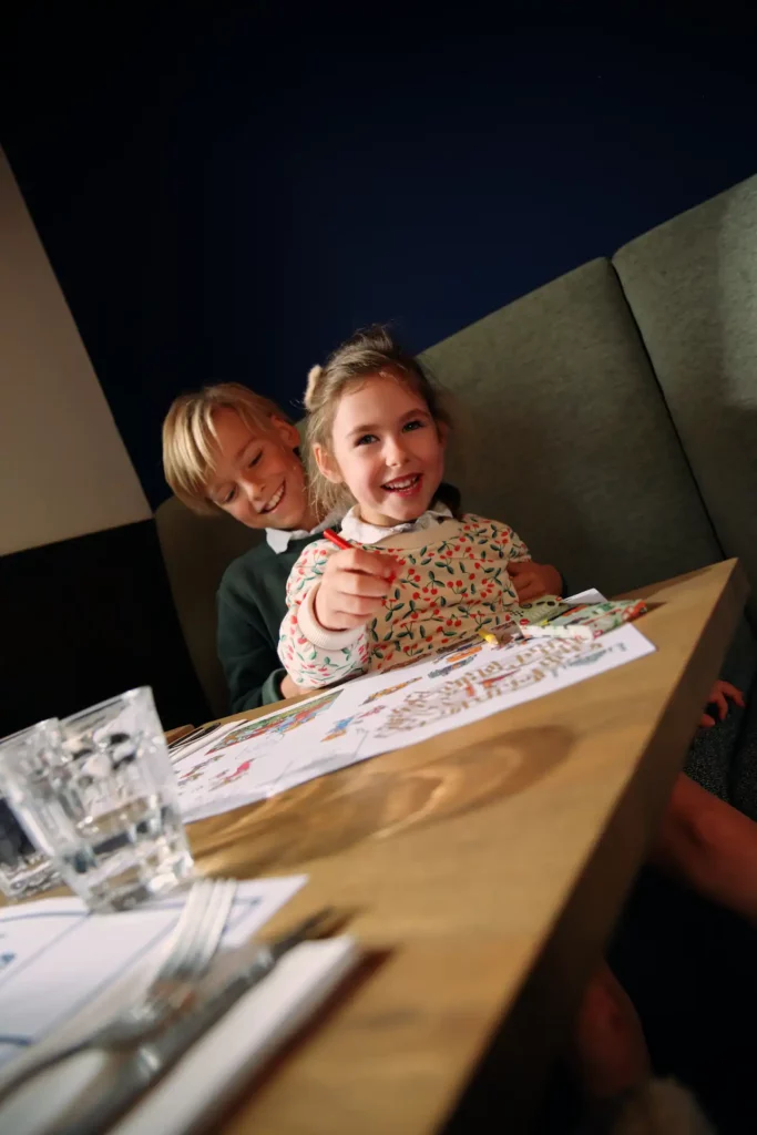 Deux enfants installés à table au restaurant Colmar, en train de colorier avant leur repas.